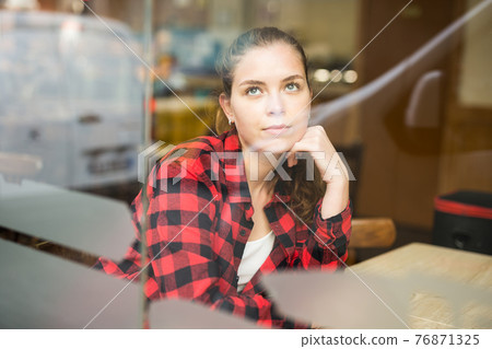 Portrait of a thoughtful girl sitting at a table in a cafe 76871325