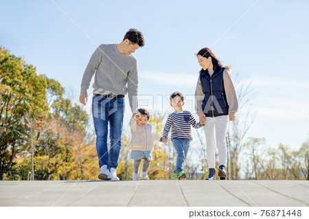 A family of four walking in a park of autumn leaves 76871448