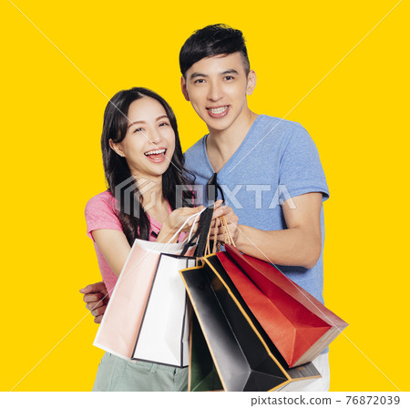 Happy young couple holding the shopping bags Happy young couple holding the shopping bags 76872039