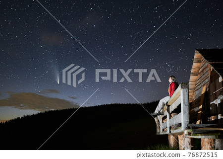 Young woman sitting under beautiful night sky with stars. Young woman sitting under beautiful night sky with stars. 76872515
