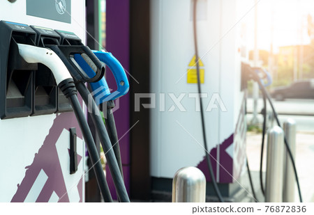 Electric car charging station for charge EV battery. Plug for vehicle with electric engine. EV charger. Clean energy. Charging point at car parking lot. Green power. Future transport technology. 76872836