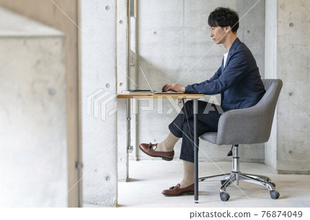A casual business image of a man in his thirties working on a laptop computer A casual business image of a man in his thirties working on a laptop computer 76874049