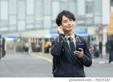 一個 30 多歲的男人戴著耳機和智能手機 76874107