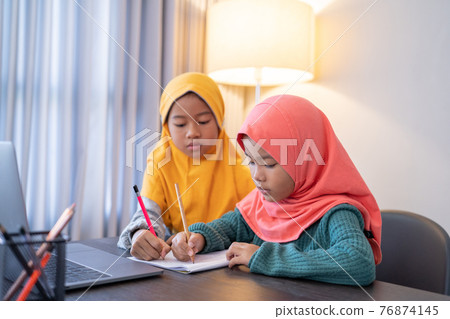 sister helping each other working on homework 76874145