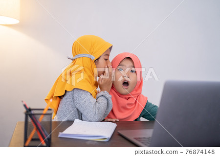 little sister whispering something to her sibling and shocked 76874148