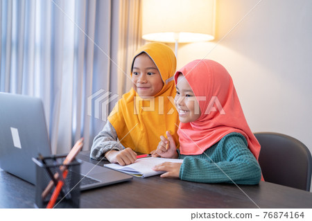 muslim children wearing head scarf smiling while using laptop computer 76874164
