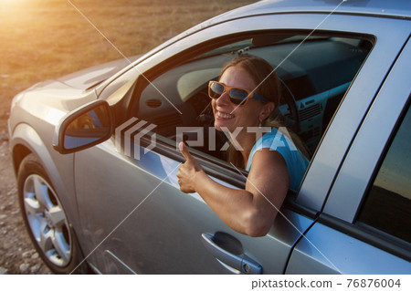 travel by car. Happy girl with glasses looks out of the car 76876004
