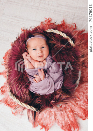 a baby in a basket sleeping and smiling 76876018
