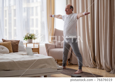 Portrait of a smiling senior man in sportswear standing at yoga asana Portrait of a smiling senior man in sportswear standing at yoga asana 76876019