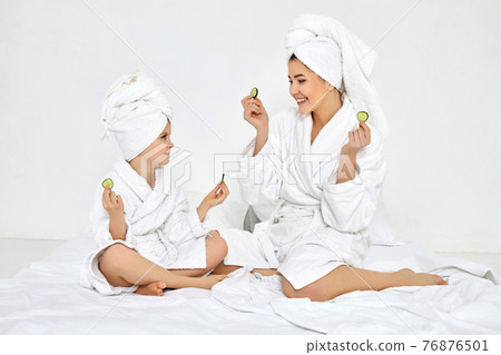mother and daughter holding fresh cucumber slices mother and daughter holding fresh cucumber slices 76876501