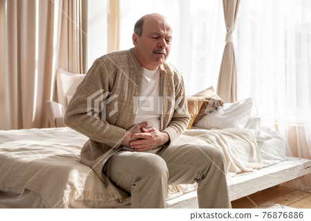 Senior man having stomach pain sitting at home. 76876886