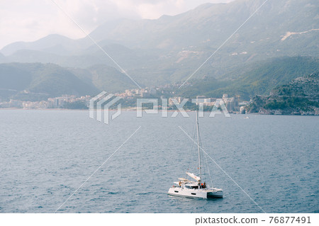 White sailing yacht floats on the sea against the background of the city in the mountains 76877491