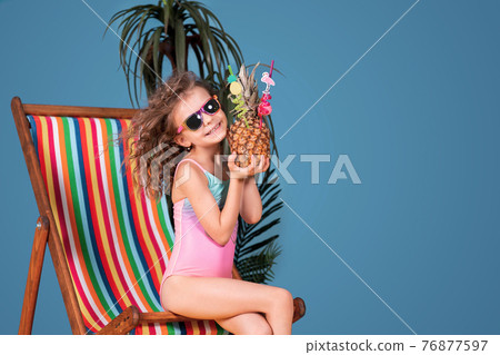 Smiling girl in swimsuit and sunglasses sitting in rainbow deck Smiling girl in swimsuit and sunglasses sitting in rainbow deck 76877597