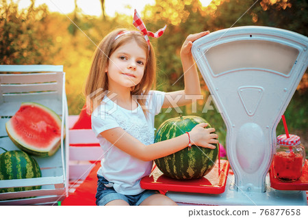 A little girl in a white T-shirt and red headband sits on a rug 76877658