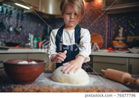 Little child girl with short hair haircut cooking dough 76877796