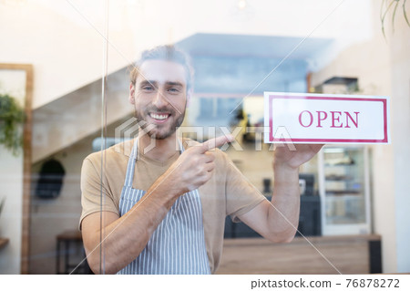 Man pointing at sign at entrance to cafe Man pointing at sign at entrance to cafe 76878272