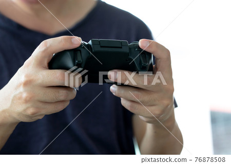 Young man holding game controller playing video games, Selected focus fingers Young man holding game controller playing video games, Selected focus fingers 76878508