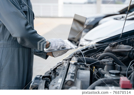 Mechanic using a laptop computer to check collect information during work a car engine. service maintenance of industrial to engine repair. Mechanic using a laptop computer to check collect information during work a car engine. service maintenance of industrial to engine repair. 76878514