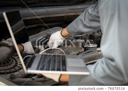 Mechanic using a laptop computer to check collect information during work a car engine. service maintenance of industrial to engine repair. Mechanic using a laptop computer to check collect information during work a car engine. service maintenance of industrial to engine repair. 76878516