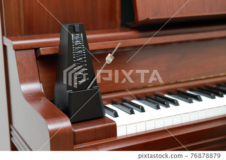 Upright piano and metronome 76878879