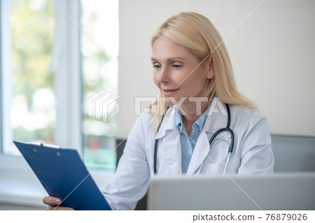 Attentive interested physician reading studying document 76879026