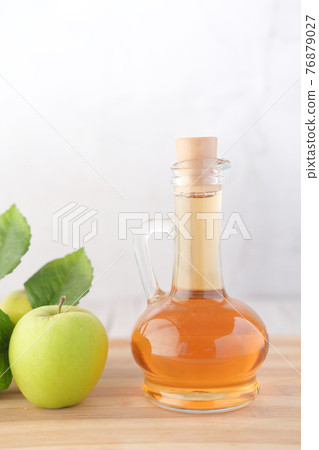 apple vinegar in glass bottle with fresh green apple on table  76879027