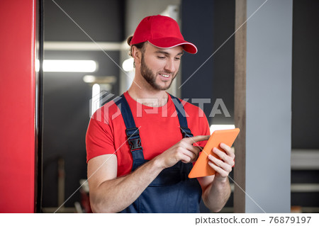 Man looking at tablet in car repair shop Man looking at tablet in car repair shop 76879197