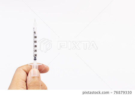 Hand holding an insulin syringe before being used Hand holding an insulin syringe before being used 76879330