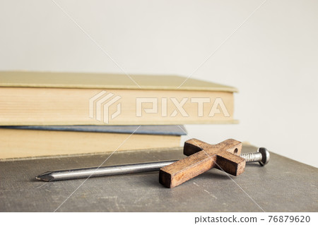 A cross with nail with bible over a light background. A cross with nail with bible over a light background. 76879620
