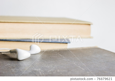 An earphone with books over the light background. An earphone with books over the light background. 76879621