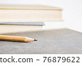 A sharp pencil over books with a light background.  76879622
