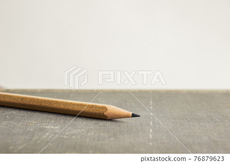 A sharp pencil over book with a light background. A sharp pencil over book with a light background. 76879623