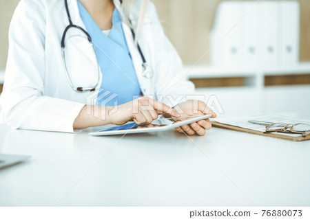 Unknown woman-doctor standing in clinic and using tablet pc, close-up. Data and best service in medicine and healthcare 76880073