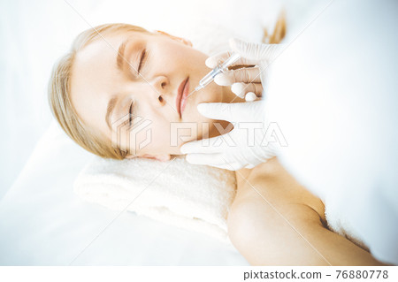 Beautician doctor doing beauty procedure with syringe to caucasian woman. Cosmetic medicine and surgery, beauty injections concept 76880778