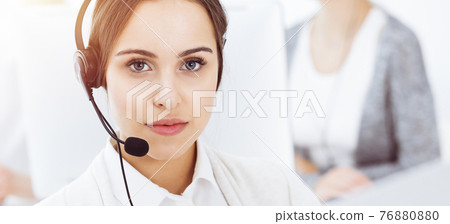 Call center in sunny office. Group of diverse operators at work. Beautiful woman in headset communicating with customers of telemarketing service Call center in sunny office. Group of diverse operators at work. Beautiful woman in headset communicating with customers of telemarketing service 76880880