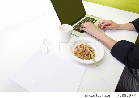 Close up of womans hands typing on laptop with mug in foreground 76880977