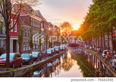 Delt canal with old houses and cars parked along on sunset 76881698