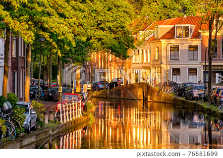 Delt canal with old houses and cars parked along on sunset 76881699
