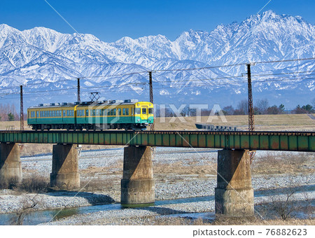 一輛黃色火車穿過以敦木山為背景的 Joganji 河鐵橋 富山千穗鐵路的風景 一輛黃色火車穿過以敦木山為背景的 Joganji 河鐵橋 富山千穗鐵路的風景 76882623