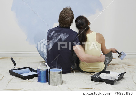 Rear View Of Couple Looking At Paint On Wall 76883986