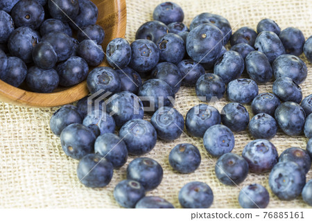 Blueberries in a wooden bowl scattered on a rustic table 76885161