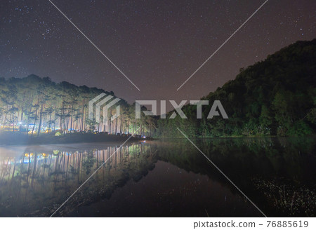 River lake with forest trees in Pang Ung reservoir at night with stars, Mae Hong Son, Thailand. Tourist attraction, surrounded by green pine, mountains, reflection from water. River lake with forest trees in Pang Ung reservoir at night with stars, Mae Hong Son, Thailand. Tourist attraction, surrounded by green pine, mountains, reflection from water. 76885619