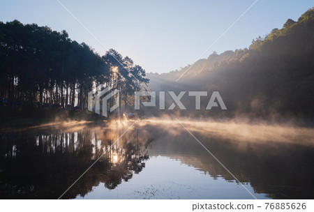 Fog or mist on river lake with forest trees in Pang Ung reservoir, Mae Hong Son, Thailand. Tourist attraction, surrounded by green pine, mountains, reflection from water. Fog or mist on river lake with forest trees in Pang Ung reservoir, Mae Hong Son, Thailand. Tourist attraction, surrounded by green pine, mountains, reflection from water. 76885626