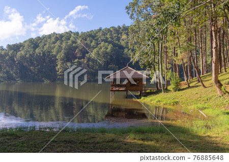 Waterfront pavilion house with lake and forest trees, Pang Ung, Mae Hong Son, Thailand. Tourist attraction in green scenery, nature view of sun reflection. 76885648