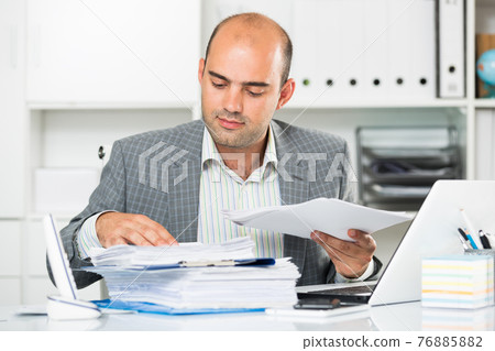 Portrait of male worker in the office sitting Portrait of male worker in the office sitting 76885882