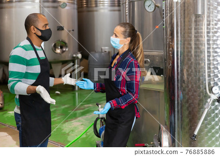 Communication of winery workers in protective masks in production shop Communication of winery workers in protective masks in production shop 76885886