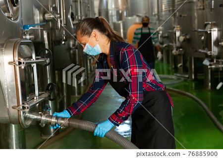 Female worker in mask working at winery Female worker in mask working at winery 76885900