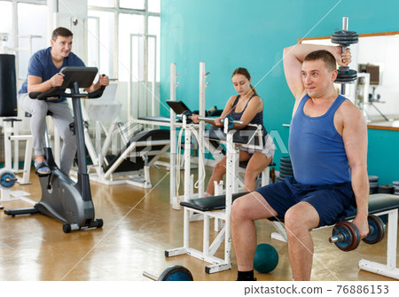 Portrait of man lifting dumbbells at gym Portrait of man lifting dumbbells at gym 76886153