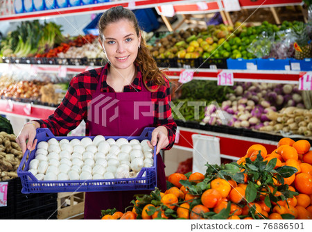 Portrait of a saleswoman holding a box of mushrooms 76886501