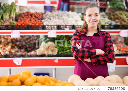Portrait of smiling girl seller standing at counter in store Portrait of smiling girl seller standing at counter in store 76886608